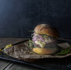 Leckere Hamburger mit Linsen und lila Karotten auf Tablett mit Pergament — Stockfoto