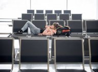 Donna turistica sdraiata e sdraiata su panchina nel terminal dell'aeroporto — Foto stock