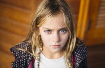 Ritratto di ragazza bionda con gli occhi azzurri in piedi sfondo di legno — Foto stock