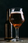 Glas Bier auf dunklem Hintergrund mit Bierflasche — Stockfoto
