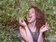 Charming young woman in bra trying to lick tree leaves while standing in garden — Stock Photo