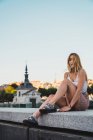 Giovane donna in abito casual guardando la fotocamera mentre seduto sullo sfondo della città — Foto stock