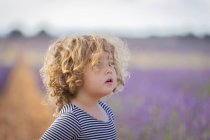 Entzückendes kleines Mädchen schaut weg in lila Lavendelfeld — Stockfoto