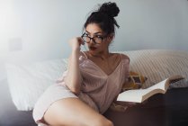 Чуттєва мрійлива жінка з книгою, що охолоджує на ліжку — стокове фото