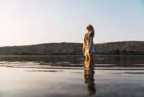 Dreamy woman standing in clear water of lake — Stock Photo