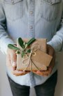 Man holding homemade wrapped Present decorated with green branch — Stock Photo