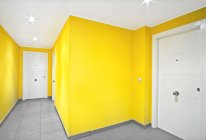 Paredes amarelas e portas brancas do corredor estreito no edifício moderno — Fotografia de Stock