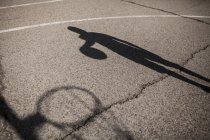 Sombra de menino jogando basquete na quadra ao ar livre — Fotografia de Stock