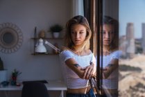 Pretty pensive woman standing near window and looking away — Stock Photo