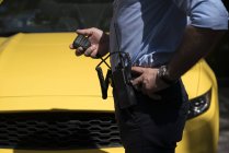 Homem de uniforme com rádio portátil definido patrulhando o tráfego rodoviário e de pé contra o carro na rua — Fotografia de Stock