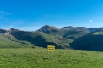 Paesaggio verde di montagne e cartello giallo che mostra diversione con frecce in direzioni diverse sotto il cielo blu — Foto stock