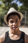 Portrait de jeune garçon en chapeau de paille debout à l'extérieur et regardant la caméra — Photo de stock