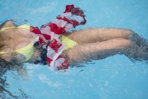 Mujer nadando en piscina con bandera americana - foto de stock