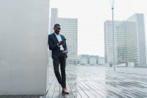 Афро-американських бізнесмен за допомогою смартфона стоячи в сучасне місто — стокове фото