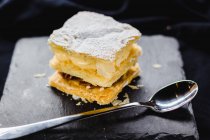 Puff pastry dessert with cream on slate on black fabric — Stock Photo