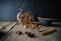 Frasco virado de granola deliciosa com especiarias chai na mesa de madeira com tigela e vários aromas — Fotografia de Stock
