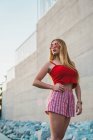 Elegante giovane donna in pantaloncini e canotta rossa contro muro di cemento — Foto stock