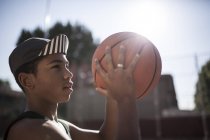 Young afro boy in cap playing basketball on court of neighborhood — Stock Photo