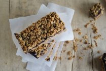 Homemade stacked granola bars on baking parchment on wooden surface — Stock Photo
