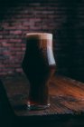 Stout beer in glass on wooden table on dark background — Stock Photo