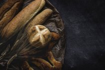 Pão cozido na hora pães e espigas de trigo no fundo preto — Fotografia de Stock