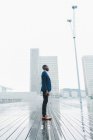 Elegant businessman standing on pavement in rain against modern city buildings — Stock Photo
