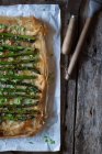 Baked asparagus pie on wooden surface with knife and brush — Stock Photo