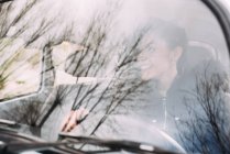 Souriant jeune femme conduisant une vieille voiture et détournant les yeux — Photo de stock