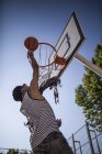 Афро-молодий хлопчик прицілюється до баскетболу в кошику на дворі на відкритому повітрі — стокове фото