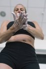 Mulher espalhando giz nas mãos durante o treinamento em ginásio — Fotografia de Stock