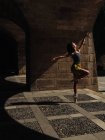 Vue latérale d'une jolie danseuse de ballet posant sur une rue ensoleillée. — Photo de stock