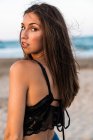 Gorgeous brunette woman in black top posing on beach — Stock Photo