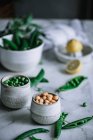 Close-up tiro de pequenos frascos cheios de ervilhas maduras em pé sobre mesa de mármore branco — Fotografia de Stock