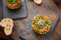 Close-up of salmon tartar with bread and decoration on slate — Stock Photo