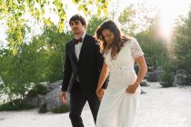 Pareja de boda caminando en la pintoresca costa - foto de stock