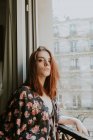 Portrait of Young woman standing at window in city — Stock Photo