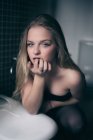 Attraktive junge Frau lehnt am Waschbecken und blickt in die Kamera. — Stockfoto