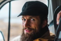 Bonito homem barbudo sorrindo e olhando para a câmera enquanto viaja pela Islândia no carro. — Fotografia de Stock