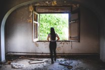Silhouette di giovane donna in piedi vicino a una bella finestra in un vecchio edificio — Foto stock