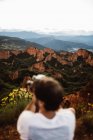 Vista posteriore del fotografo sfocato con macchina fotografica che fa foto in piedi sulle colline sullo sfondo del paesaggio in Cantabria, Spagna — Foto stock