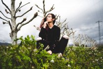 Ritratto di Dreaming giovane donna seduta in campo verde in nuvoloso — Foto stock
