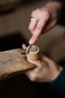 Recorte de cerca las manos de la mujer tallar detalle de madera con cuchillo en el escritorio - foto de stock
