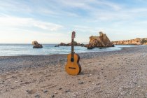 Chitarra acustica classica posta sull'oceano su una spiaggia. — Foto stock