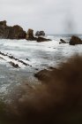 Rocks in wavy sea under gray cloudy sky in Cantabria, Spain — Stock Photo