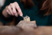 Colheita fechar as mãos da mulher esculpindo detalhes de madeira com faca na mesa — Fotografia de Stock