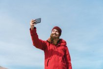 Человек, стоящий со смартфоном у гейзера — стоковое фото