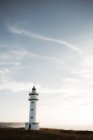 Farol retrô iluminado pelo sol sobre fundo céu azul na Cantábria, Espanha — Fotografia de Stock