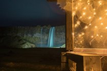 Будівля з гірляндами біля водоспаду — стокове фото