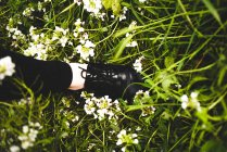Ноги в стильном черном ботинке на зеленой траве с белыми цветами — стоковое фото