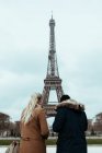 Vista posteriore della coppia in piedi alla Torre Eiffel in giornata nuvolosa a Parigi, Francia. — Foto stock